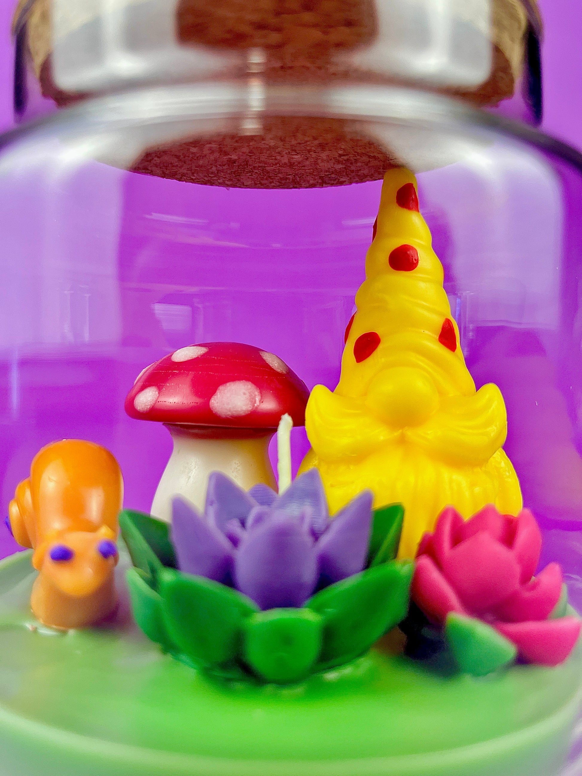 Garden gnome art candle in clear glass jar with yellow gnome, red mushroom, and flowers
