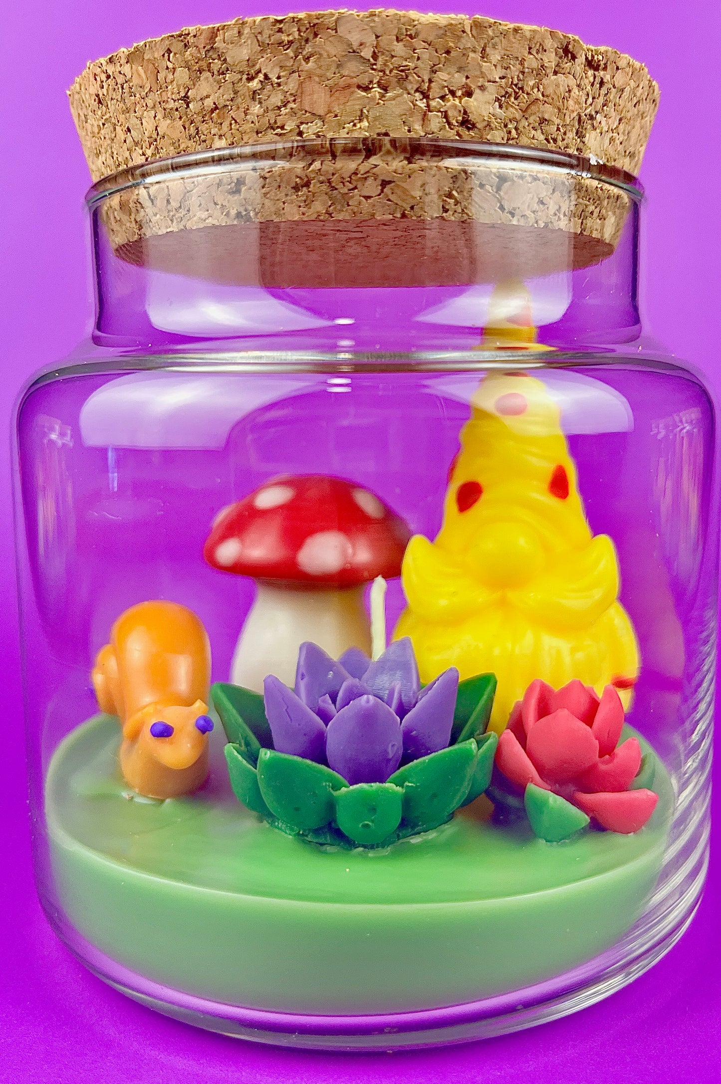 Garden gnome art candle in clear glass jar with green wax and yellow gnome and flowers