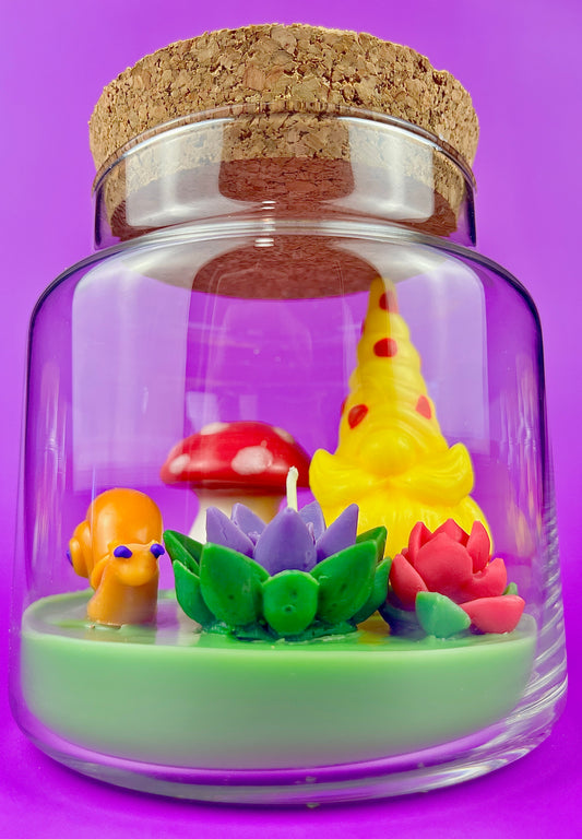 Garden gnome art candle in clear glass jar with green wax, mushroom, and flower figurines