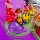 Garden gnome art candle in clear glass jar with green wax and colorful gnome figurines