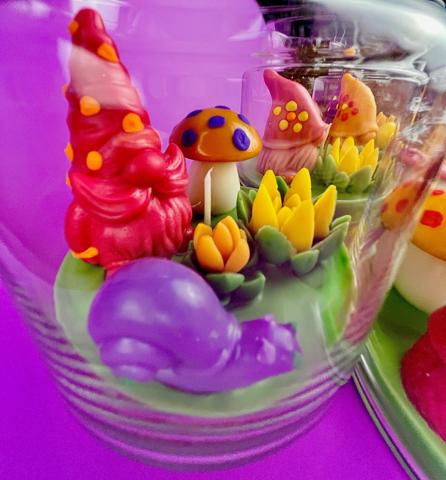 Garden gnome art candle in clear glass jar with green wax and colorful gnome figurines
