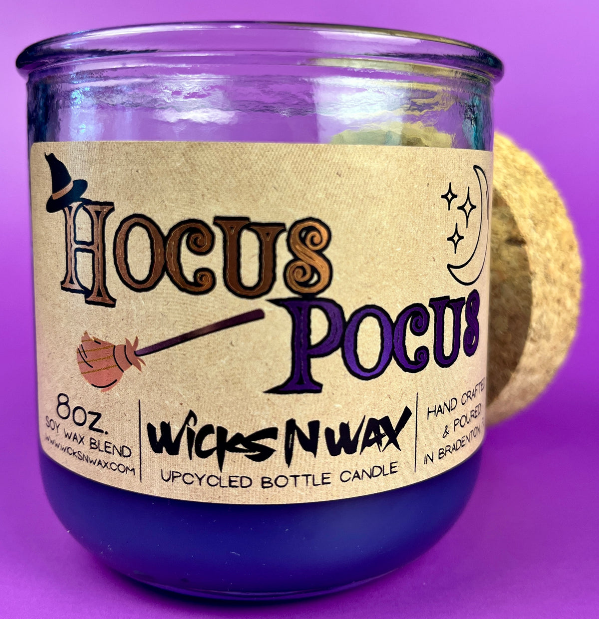 Purple glass candle jar with kraft label reading Hocus Pocus and WicksNWax