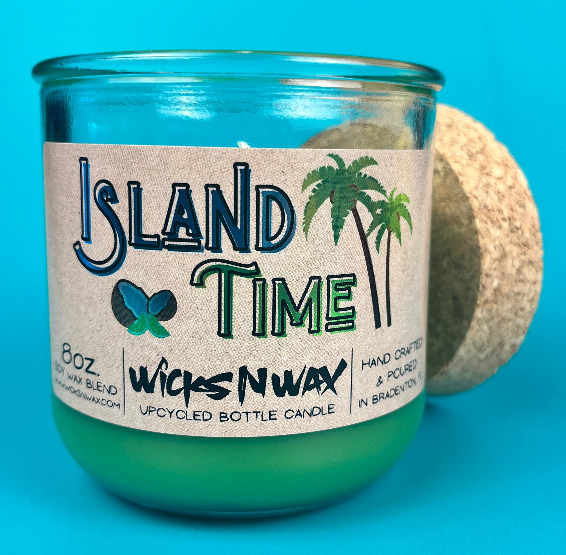 Recycled glass bottle candle with green wax and cork lid, side view of teal glass bottle.