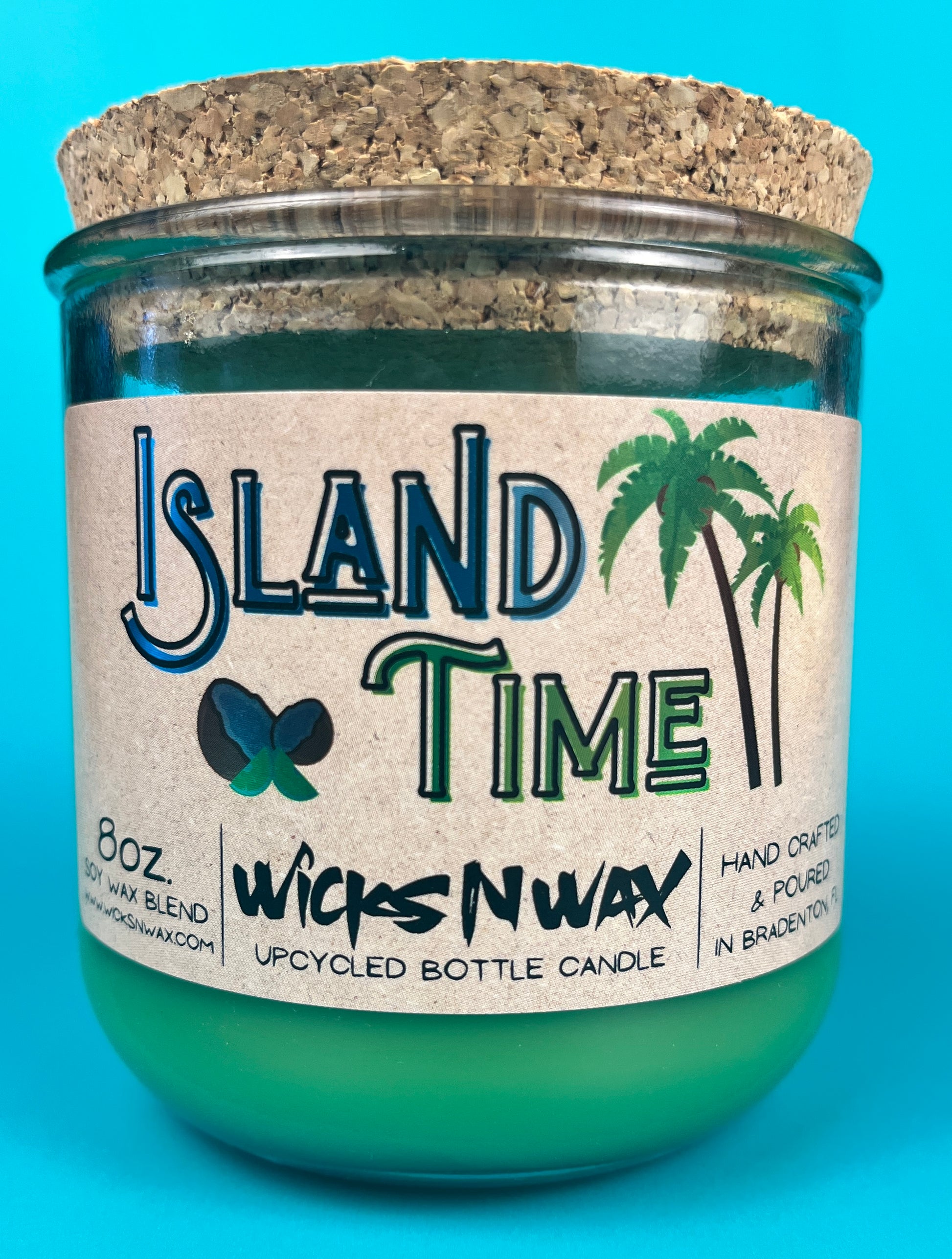 Recycled glass bottle candle with green wax and cork lid, teal glass jar centered on label.