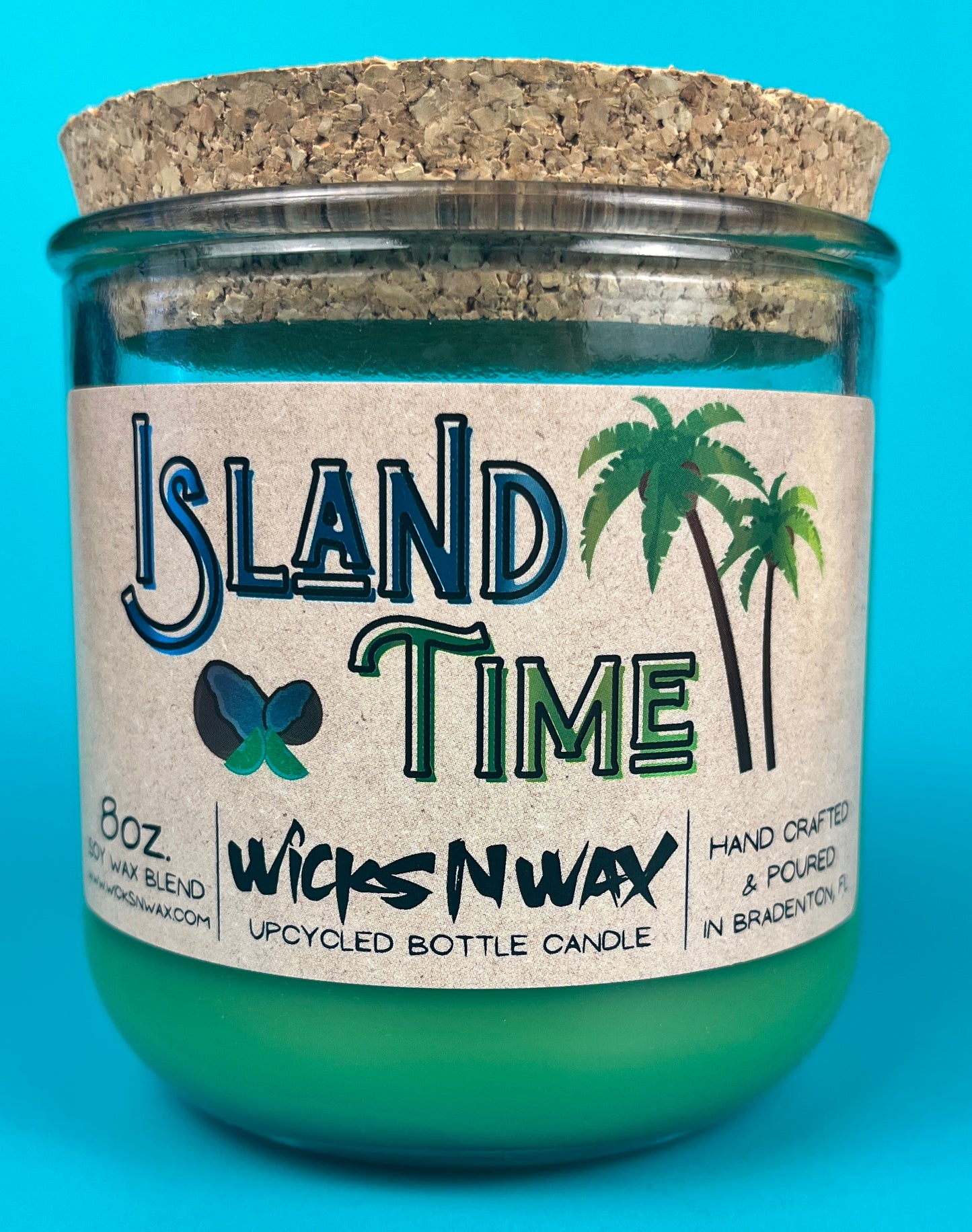 Recycled glass bottle candle with green wax and cork lid, teal glass jar with label on front.
