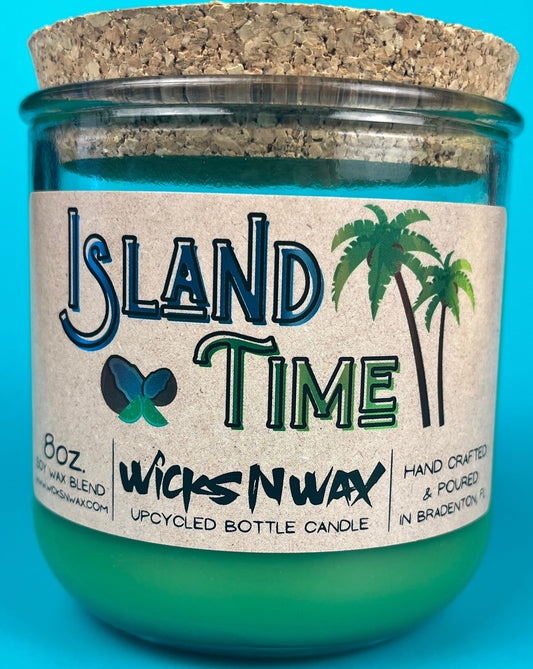 Recycled glass candle with green wax in jar, cork lid, island-themed label and WicksNWax text.