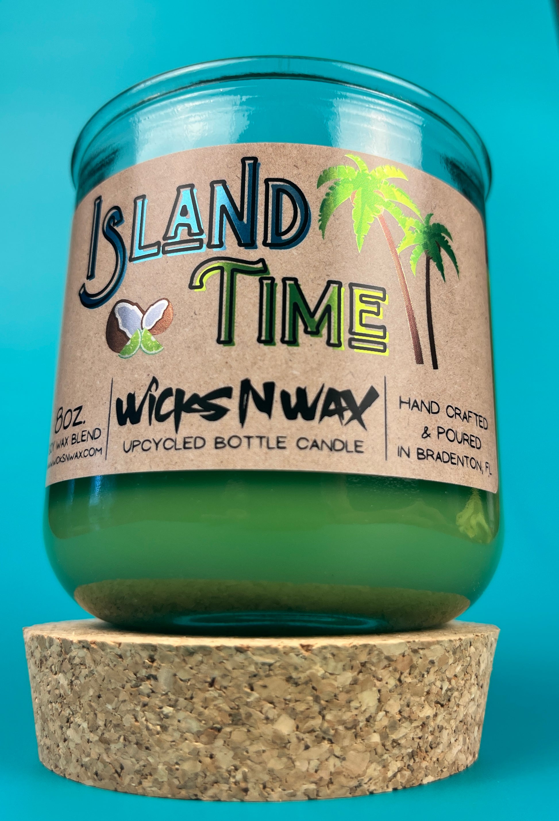 Recycled glass bottle candle with green wax and clear glass, cork base and front label.
