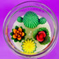 Large cactus art candle with green cactus and colorful flower wax toppers in a round bowl