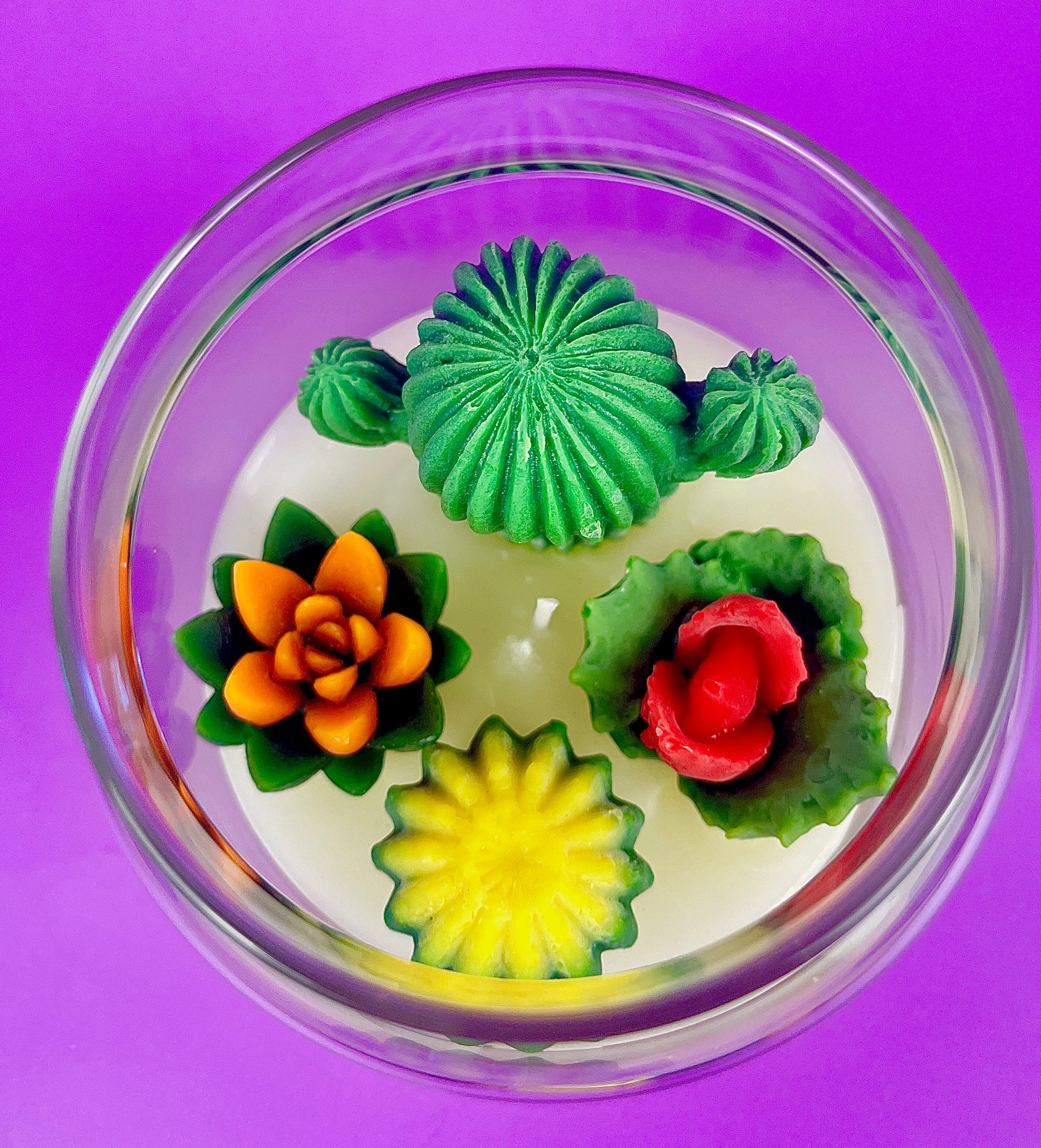 Large cactus art candle with green cactus and colorful flower wax toppers in a round bowl