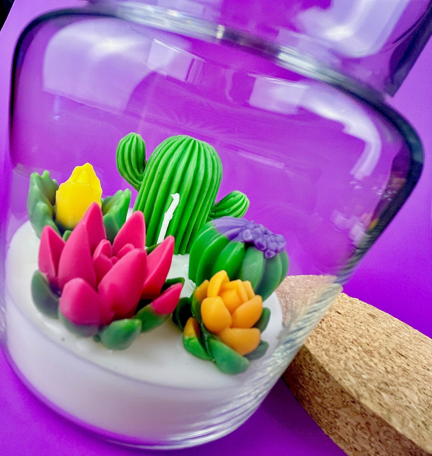 Large cactus art candle in glass jar with tall green cactus and pink, yellow, and purple flowers