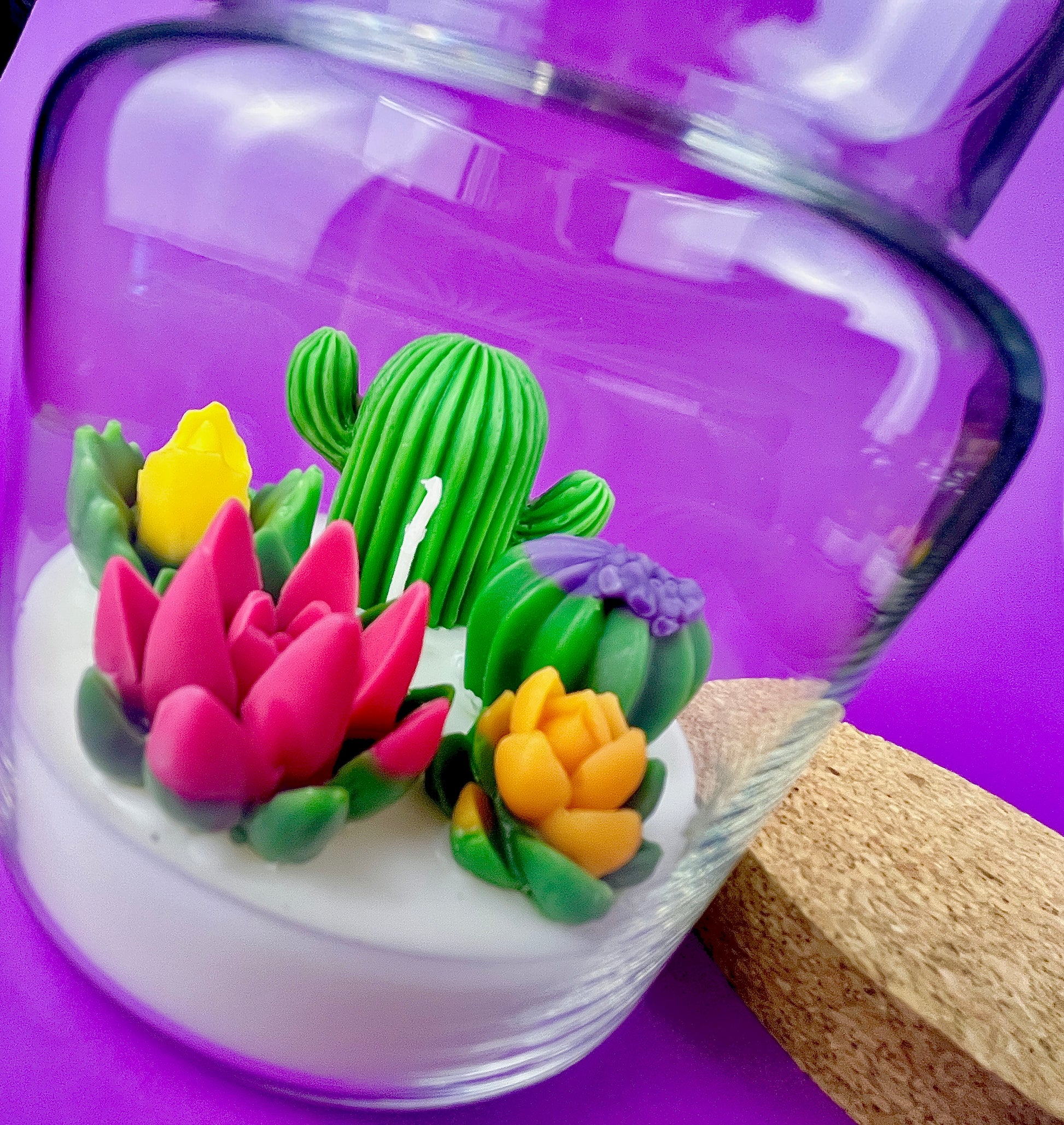 Large cactus art candle in glass jar with tall green cactus and pink, yellow, and purple flowers