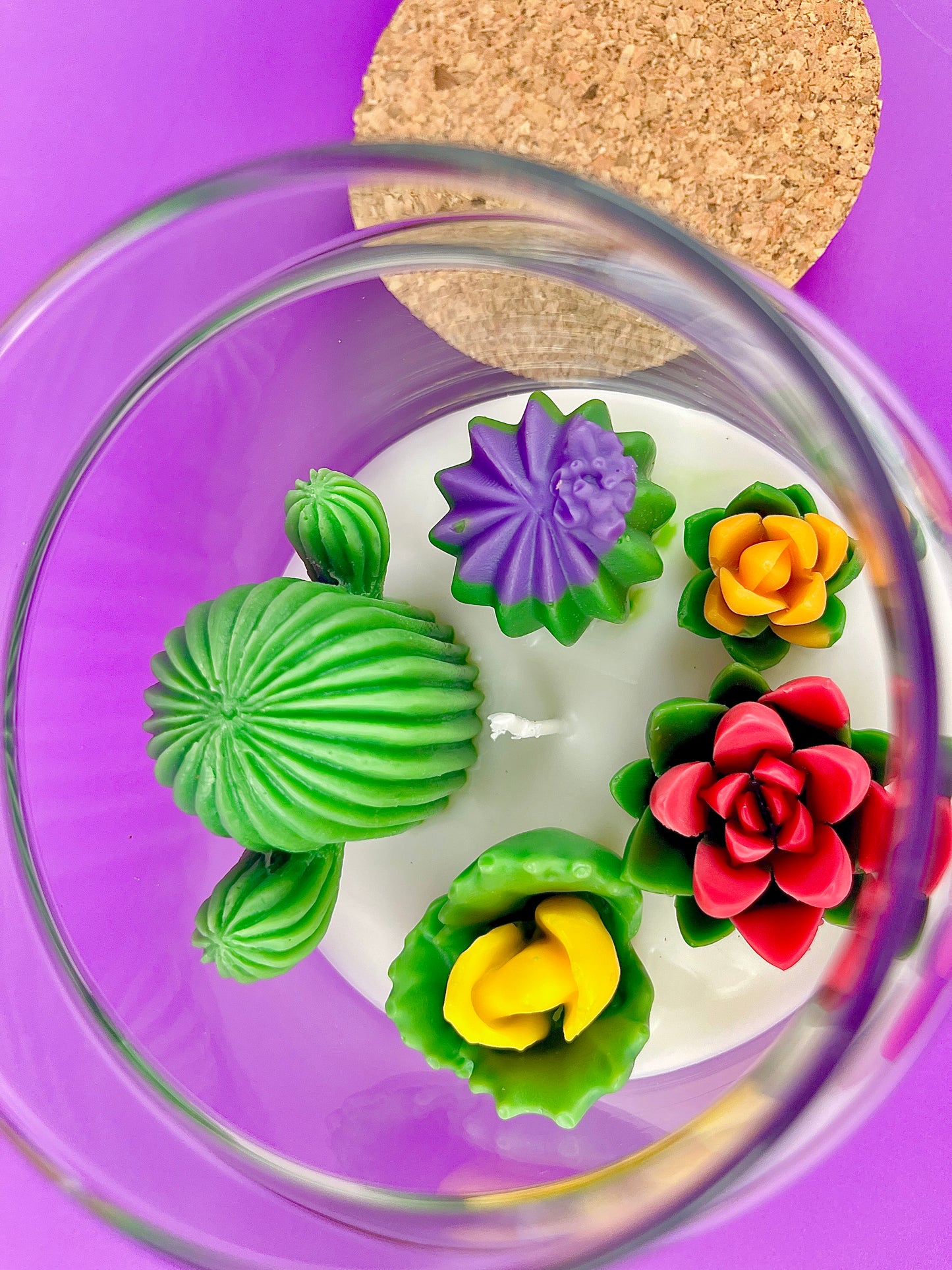 Large cactus art candle close-up in glass jar with green cactus, purple flower, and red rose waxes