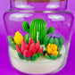 Large cactus art candle in glass jar with tall green cactus and colorful flower waxes