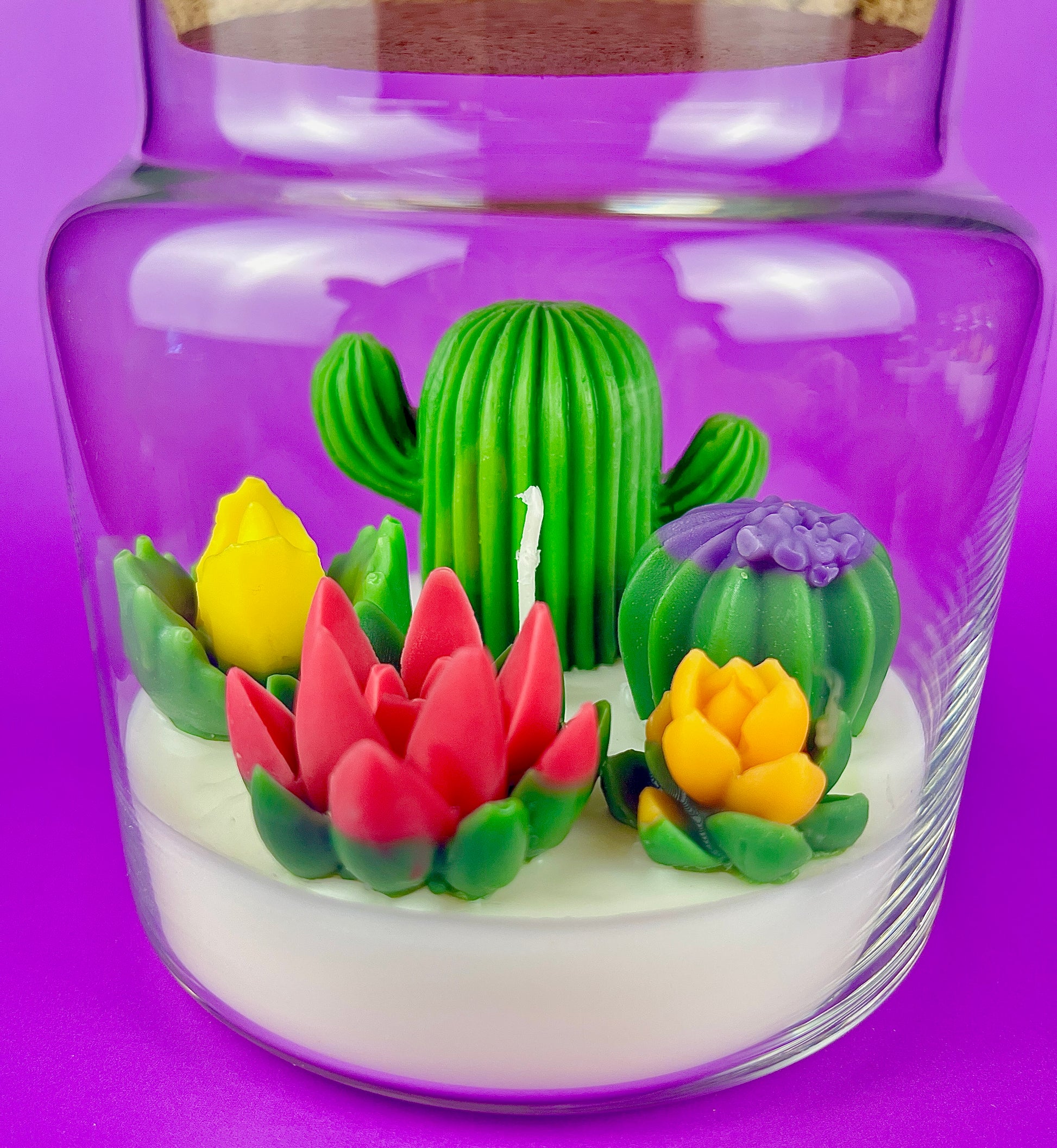 Large cactus art candle in glass jar with tall green cactus and colorful flower waxes