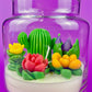 Cactus art candle in clear jar: white wax with green cactus and yellow and red floral accents