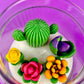 Cactus art candle close-up: white wax with green cactus and purple, orange, yellow flowers