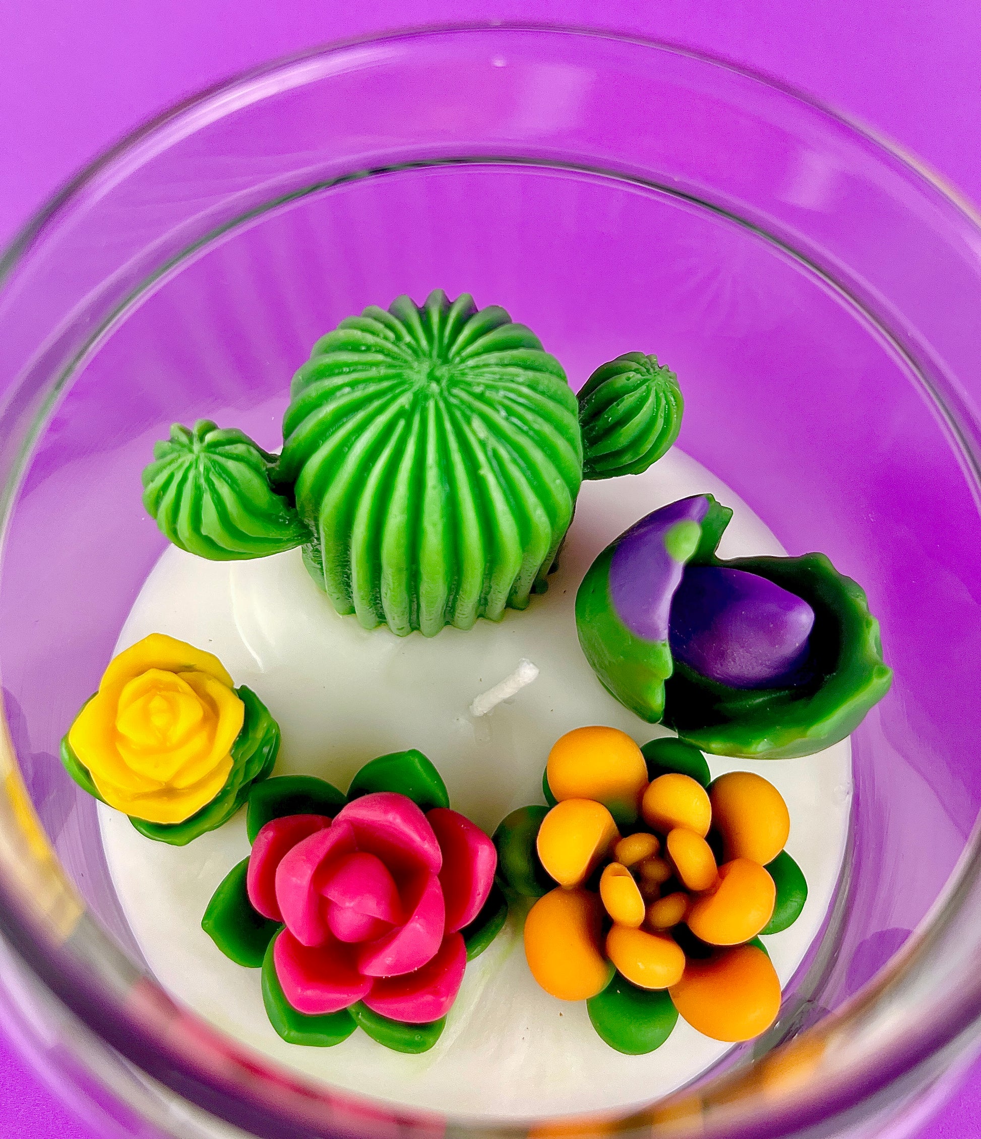 Cactus art candle close-up: white wax with green cactus and purple, orange, yellow flowers
