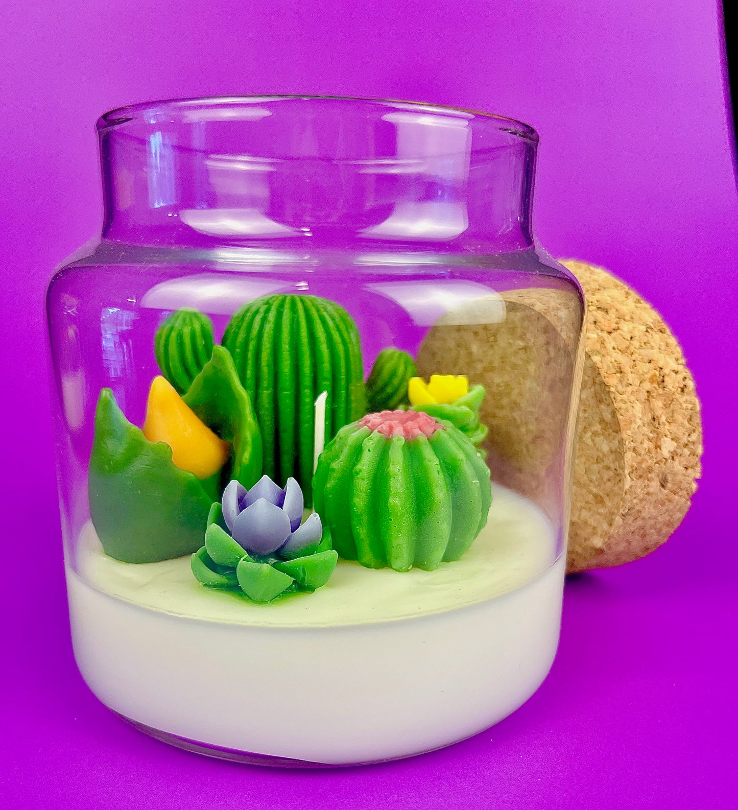 Cactus art candle in clear jar with cork lid; white wax with green cactus and blooms