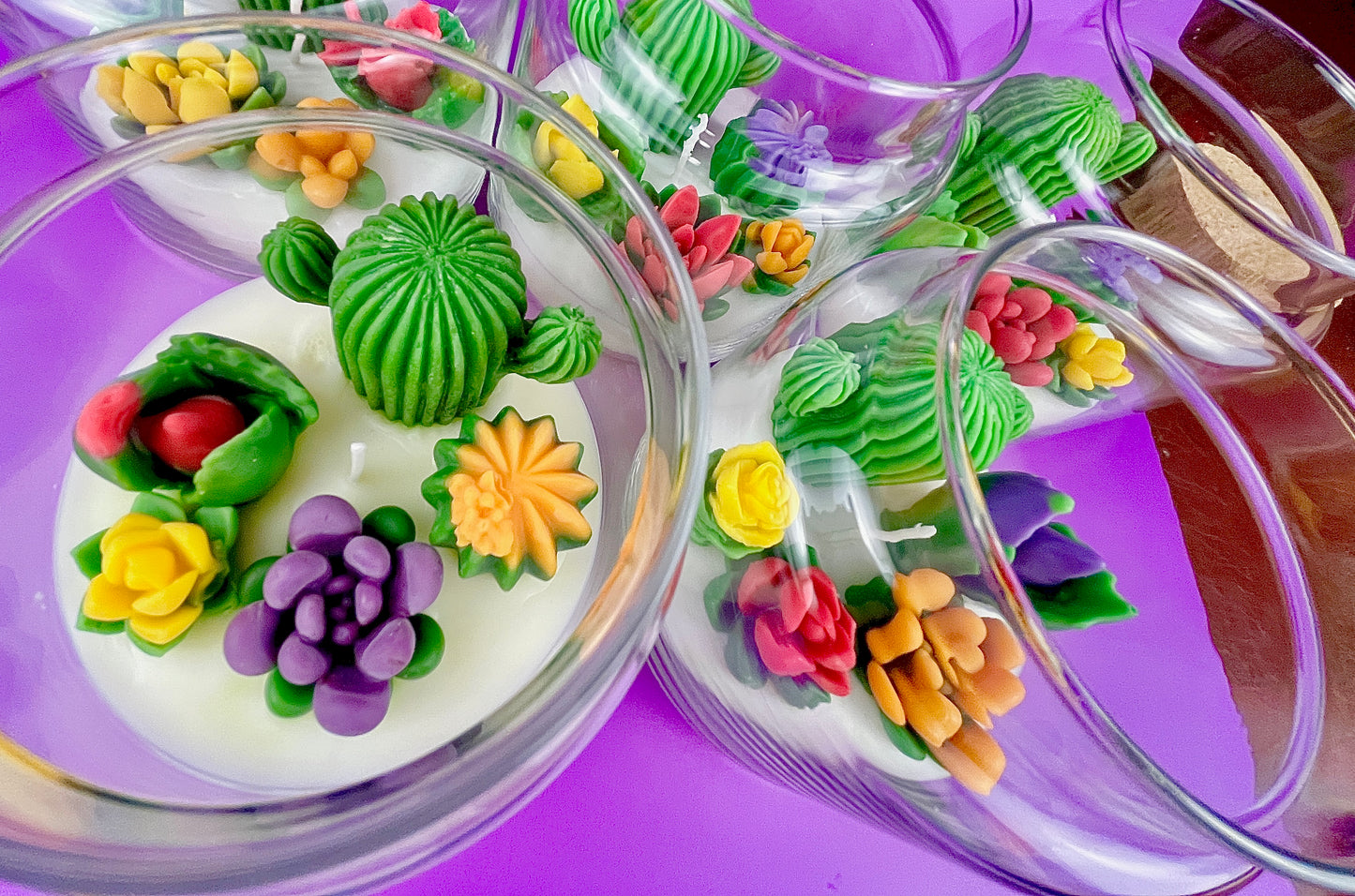 Large cactus art candles in glass jars with green cactus wax and colorful flower toppers