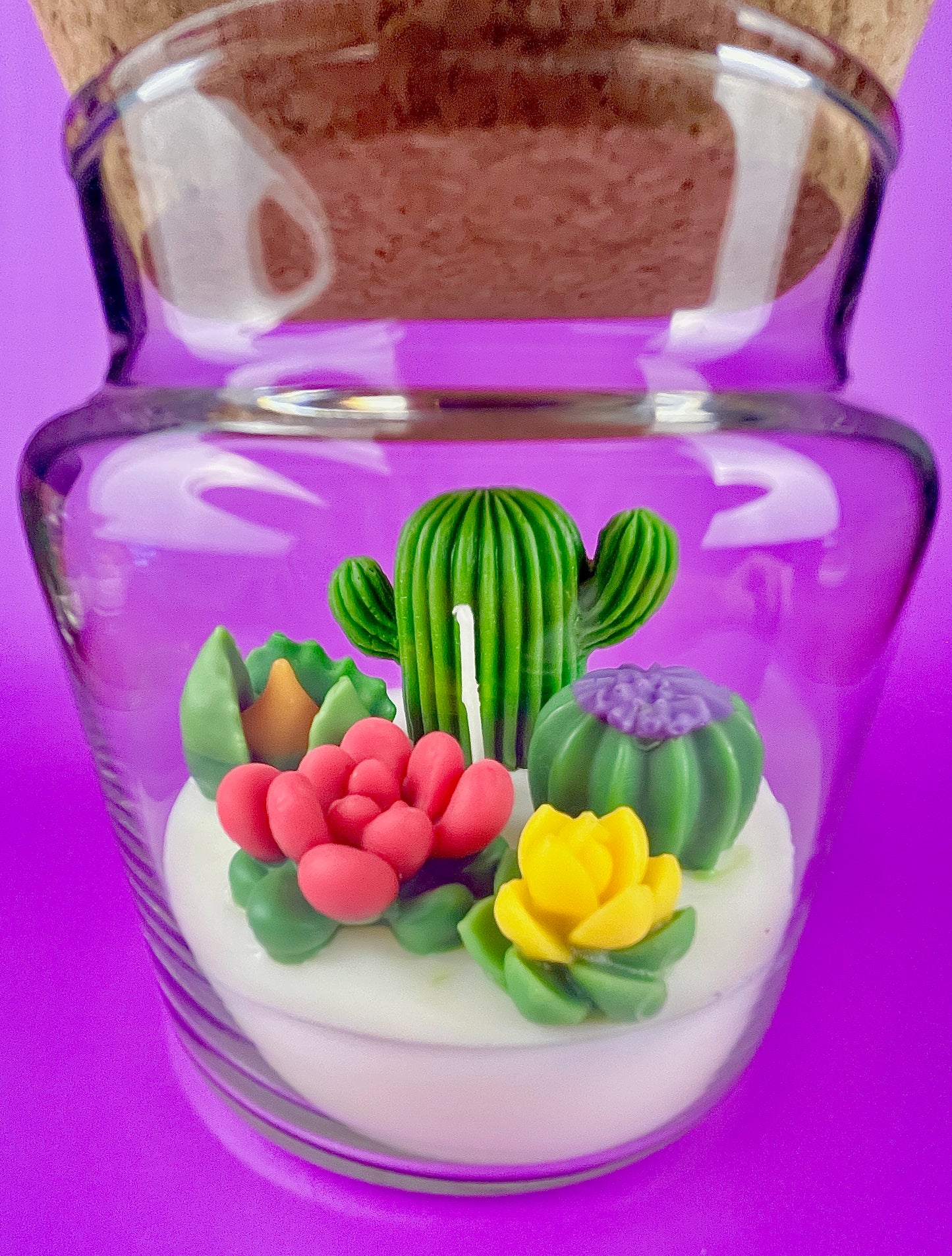 Large cactus art candle in glass jar with green cactus and pink, yellow, and purple flower waxes