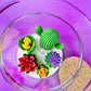 Large cactus art candle in glass jar with green cactus and red, yellow, and purple flower waxes