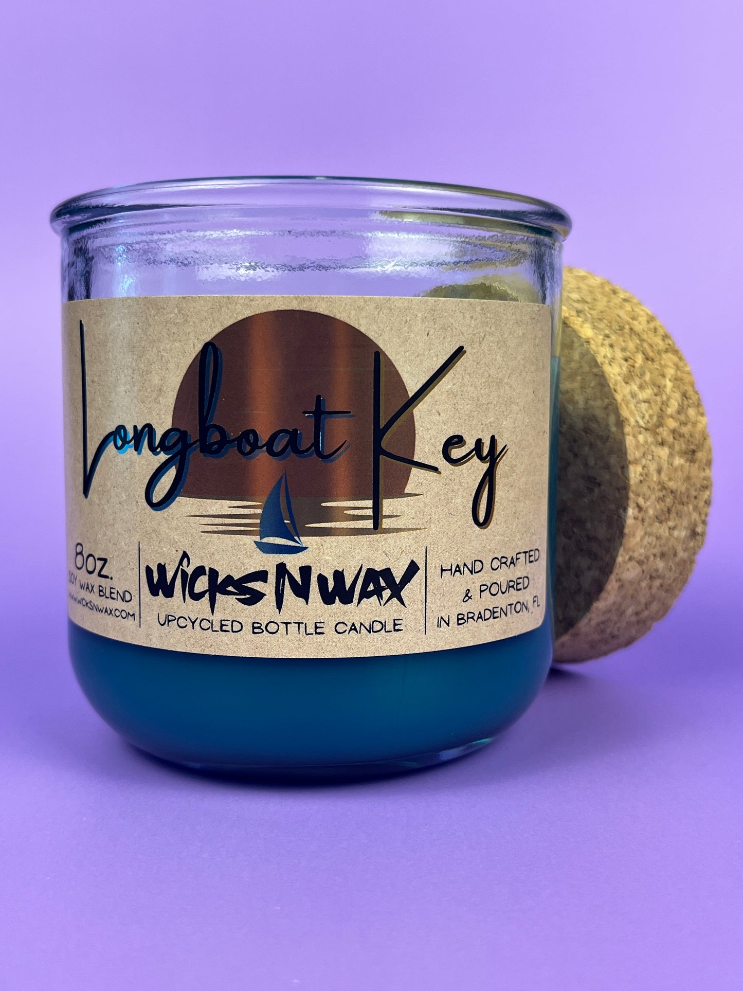 Recycled glass candle in blue wax, cork lid beside jar, front label visible
