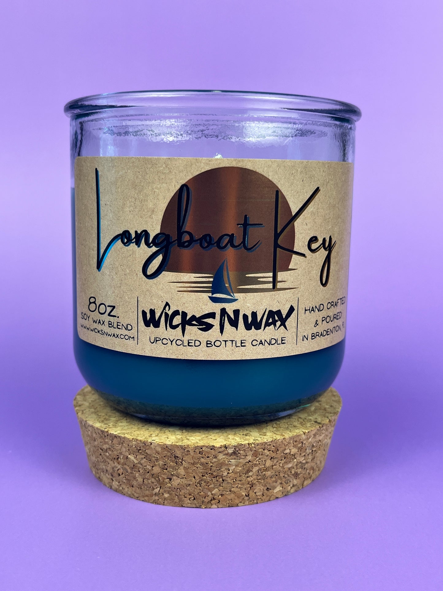 Recycled glass candle in blue wax, cork base ring under jar, front label visible