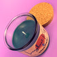 Recycled glass candle with blue wax, cork lid on side, label partly visible
