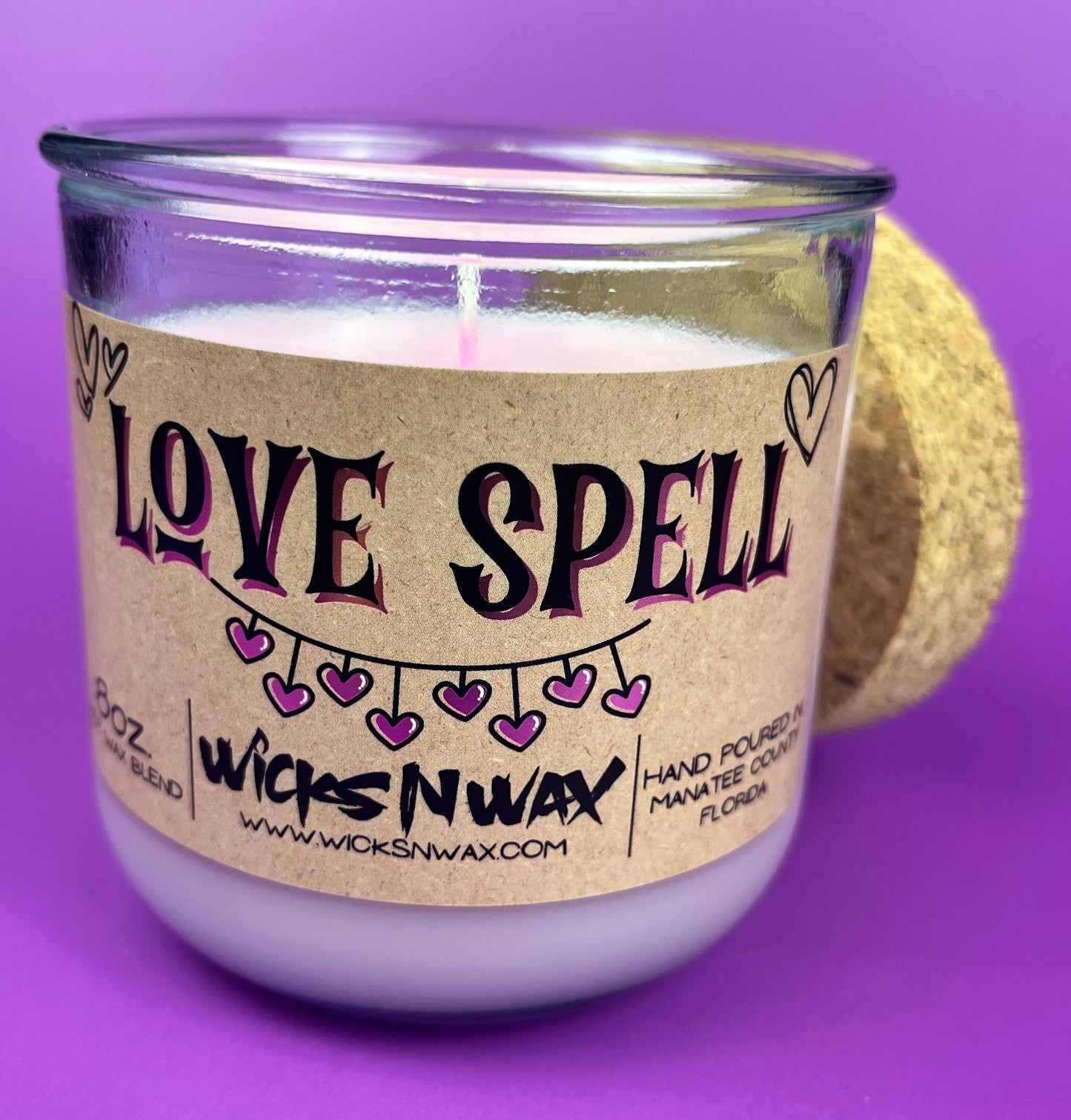 Recycled glass candle, purple jar with cork lid; beige 'LOVE SPELL' label and exposed wick