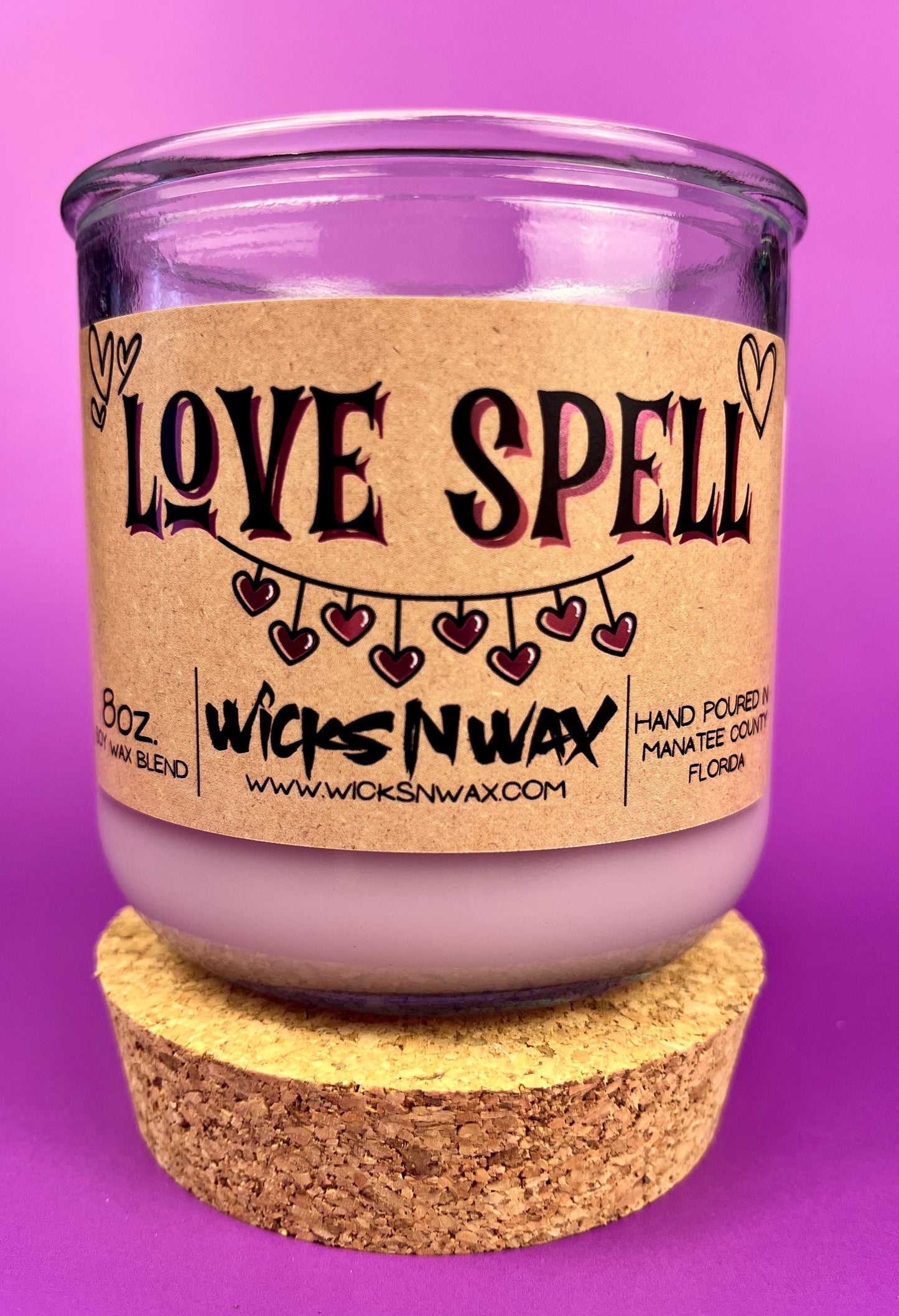 Recycled glass candle, purple jar with cork lid; beige label says 'LOVE SPELL'