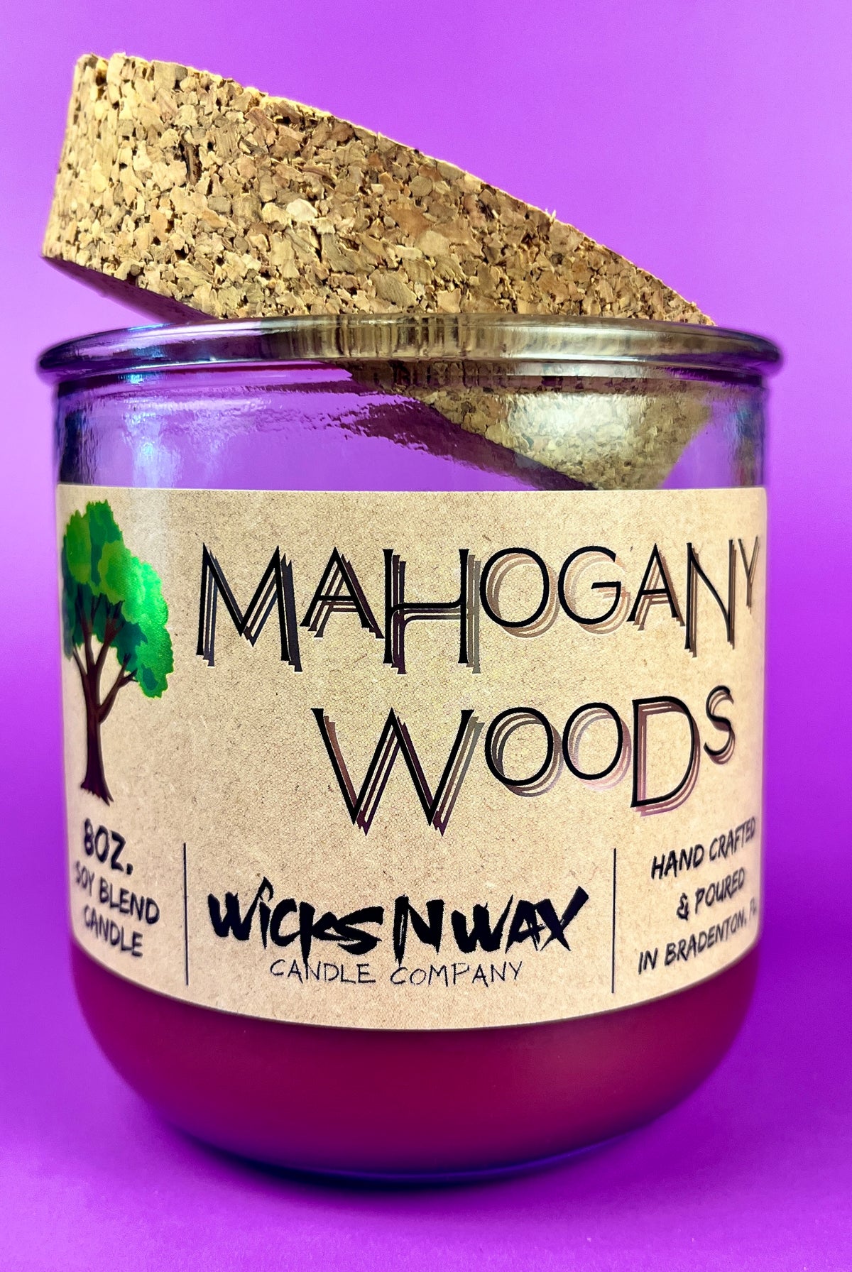 Recycled glass candle with cork lid and purple wax; side label text visible.