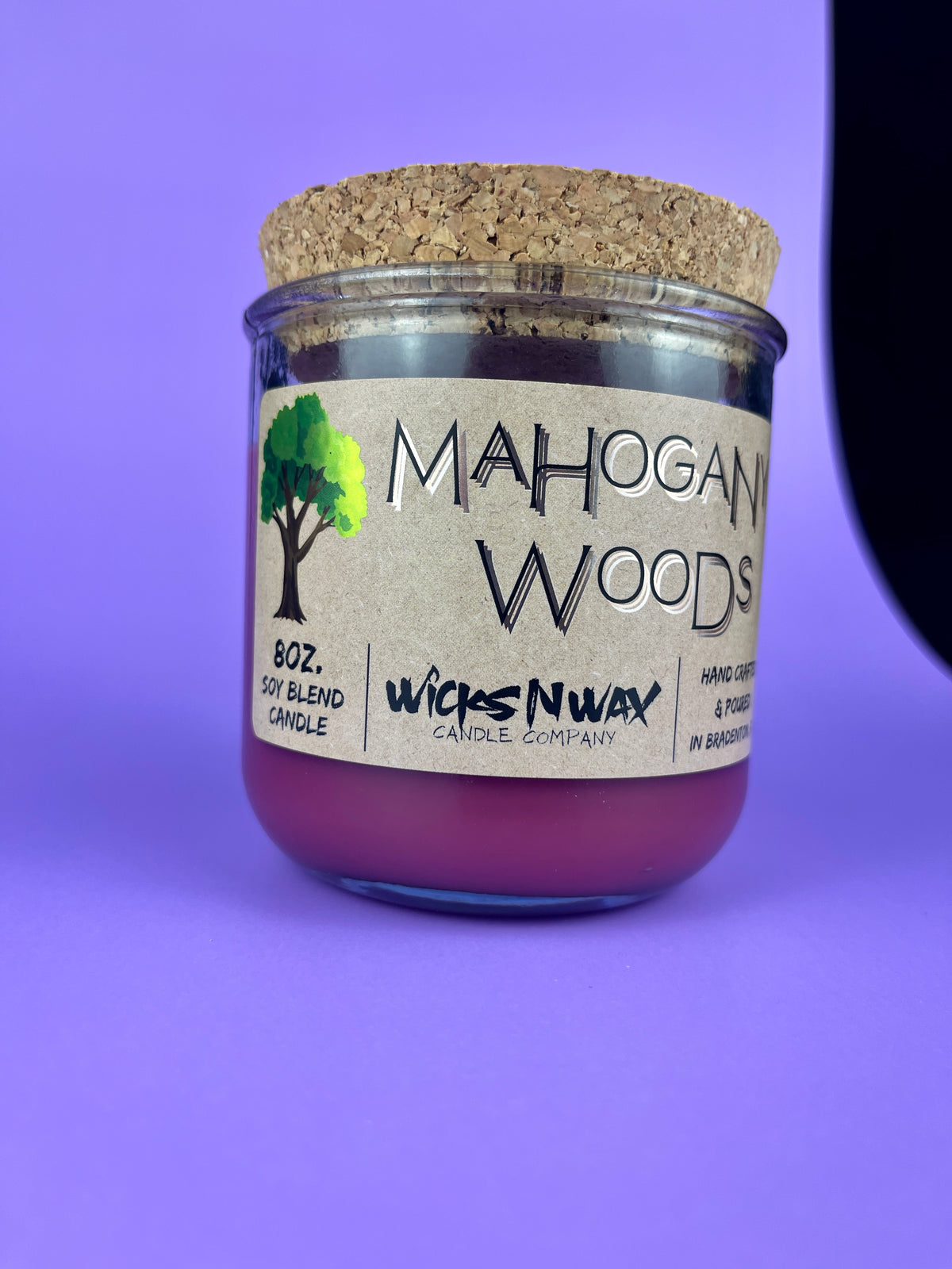 Recycled glass candle with cork lid and purple wax; side label and logo visible.