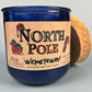 Blue glass candle jar with North Pole label, cork base edge visible, WicksNWax.