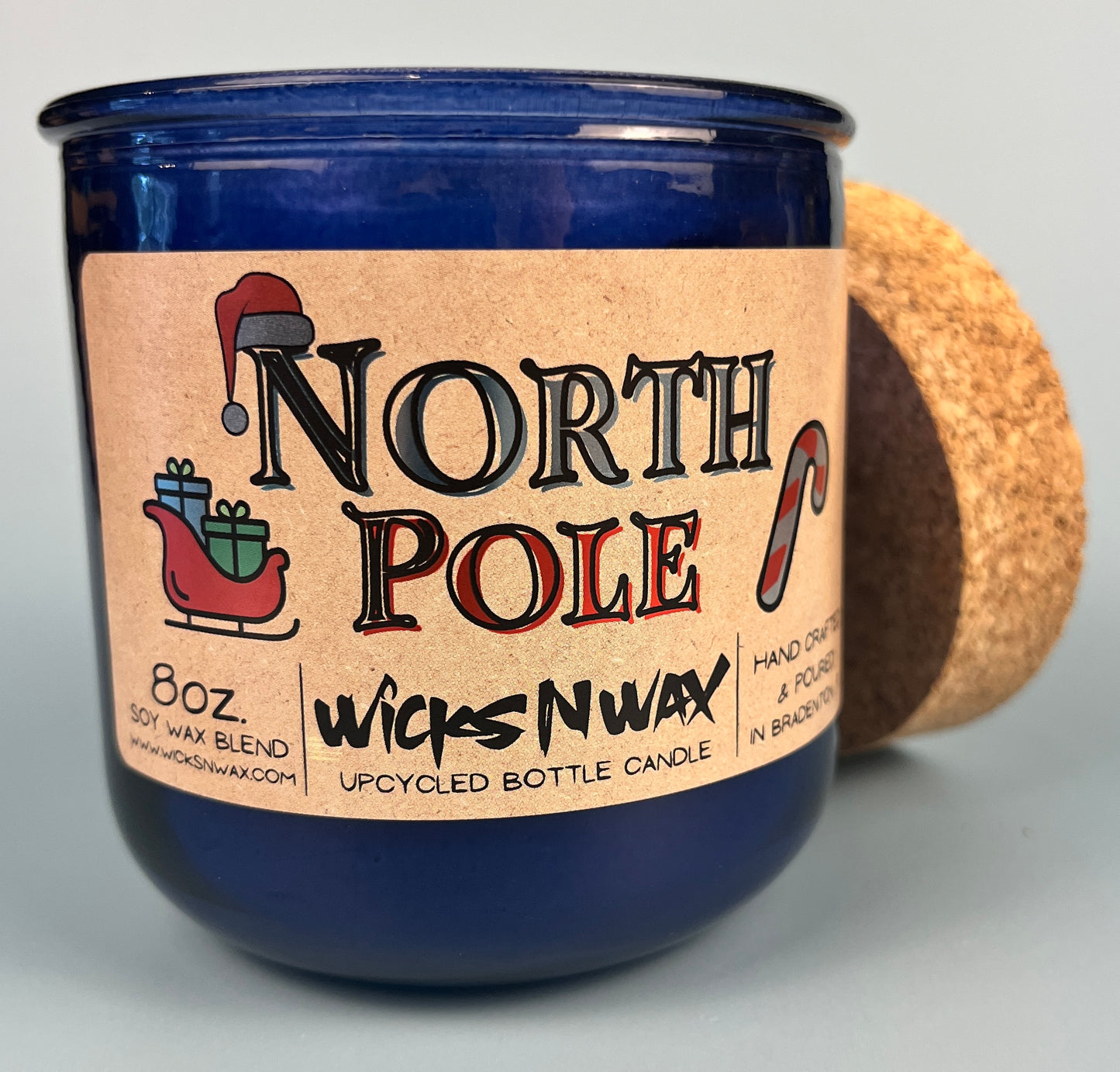 Blue glass candle jar with North Pole label, cork base edge visible, WicksNWax.