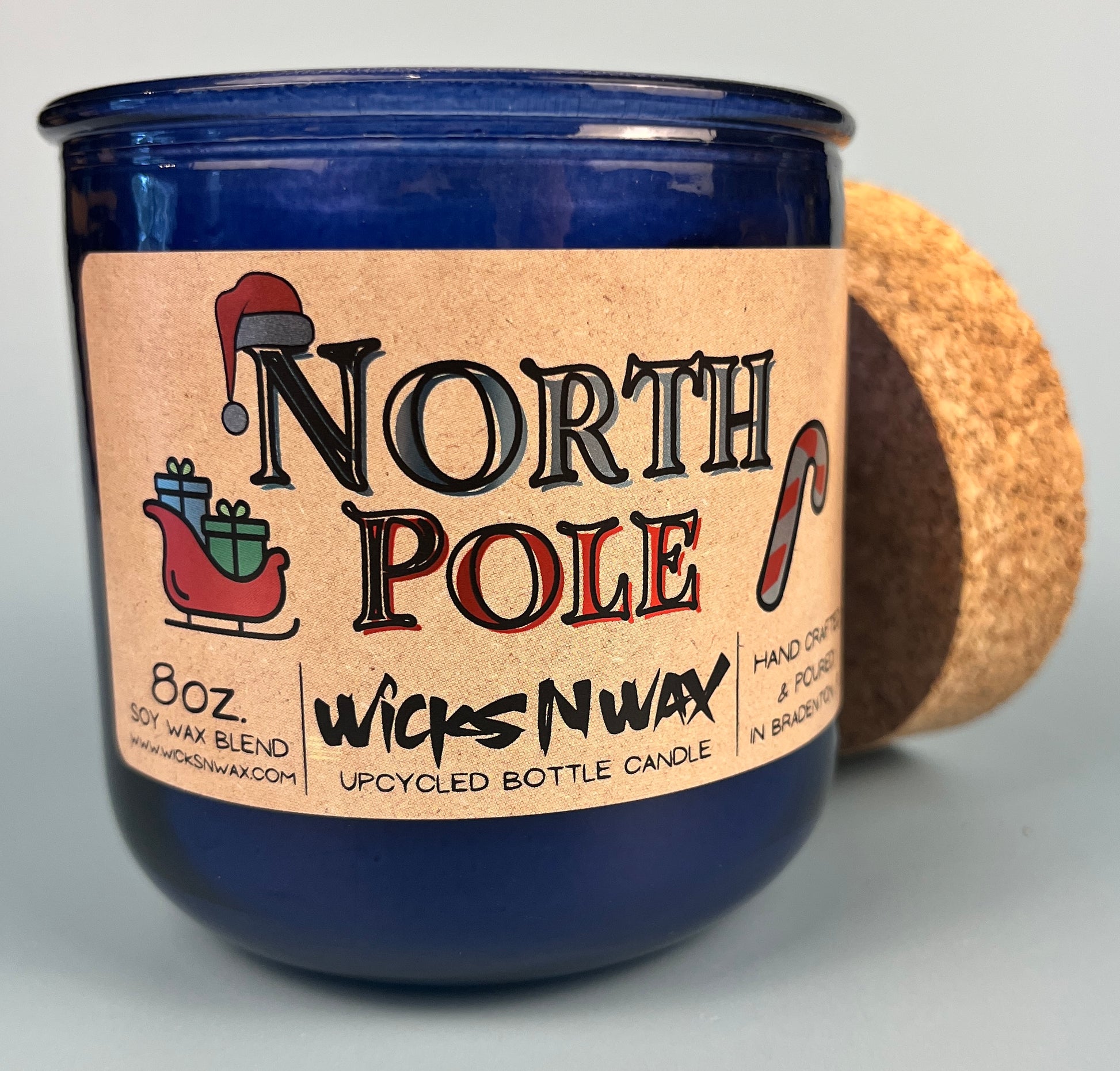 Blue glass candle jar with North Pole label, cork base edge visible, WicksNWax.