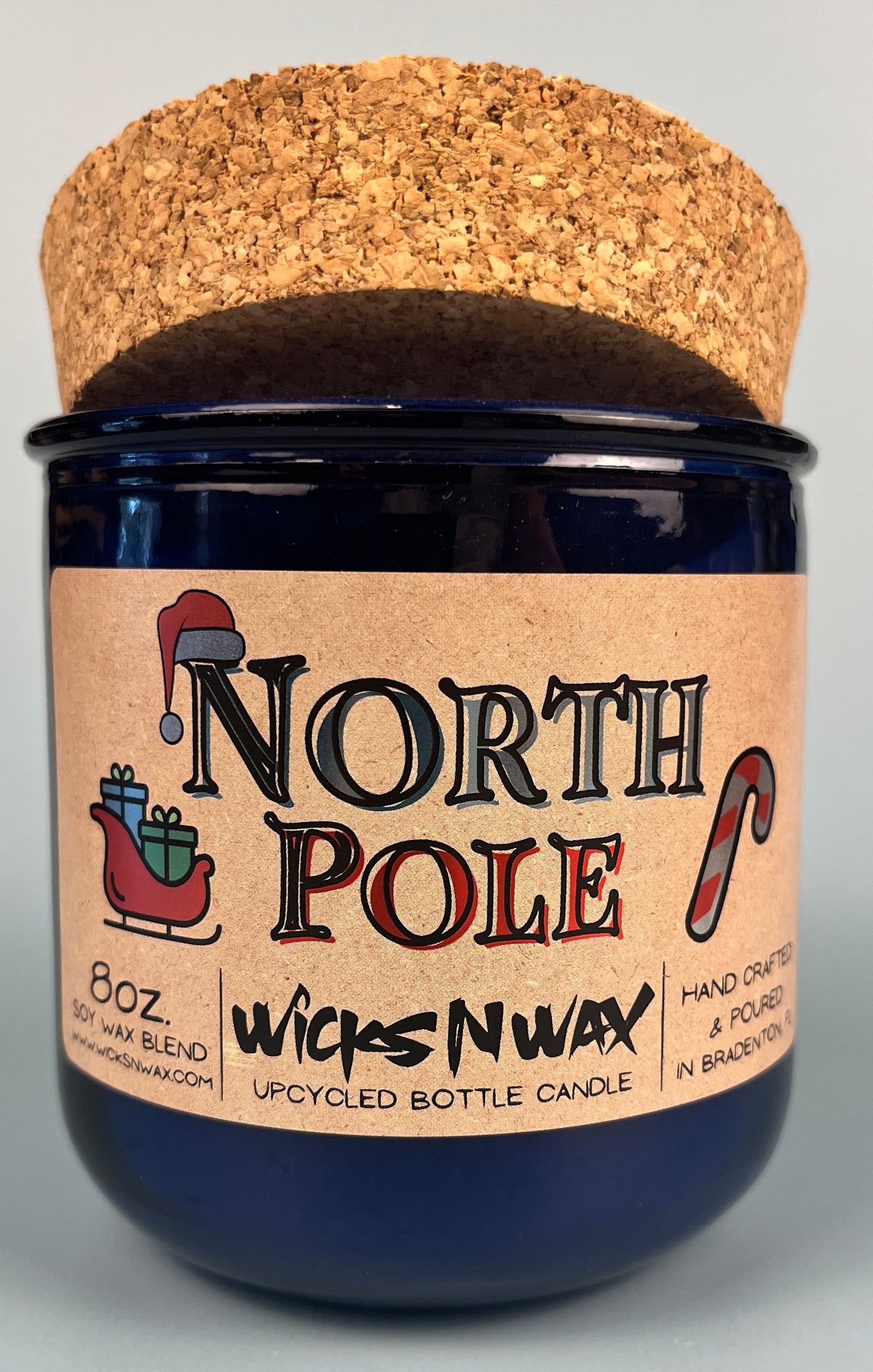 Blue glass candle jar on cork base with North Pole label and WicksNWax logo.
