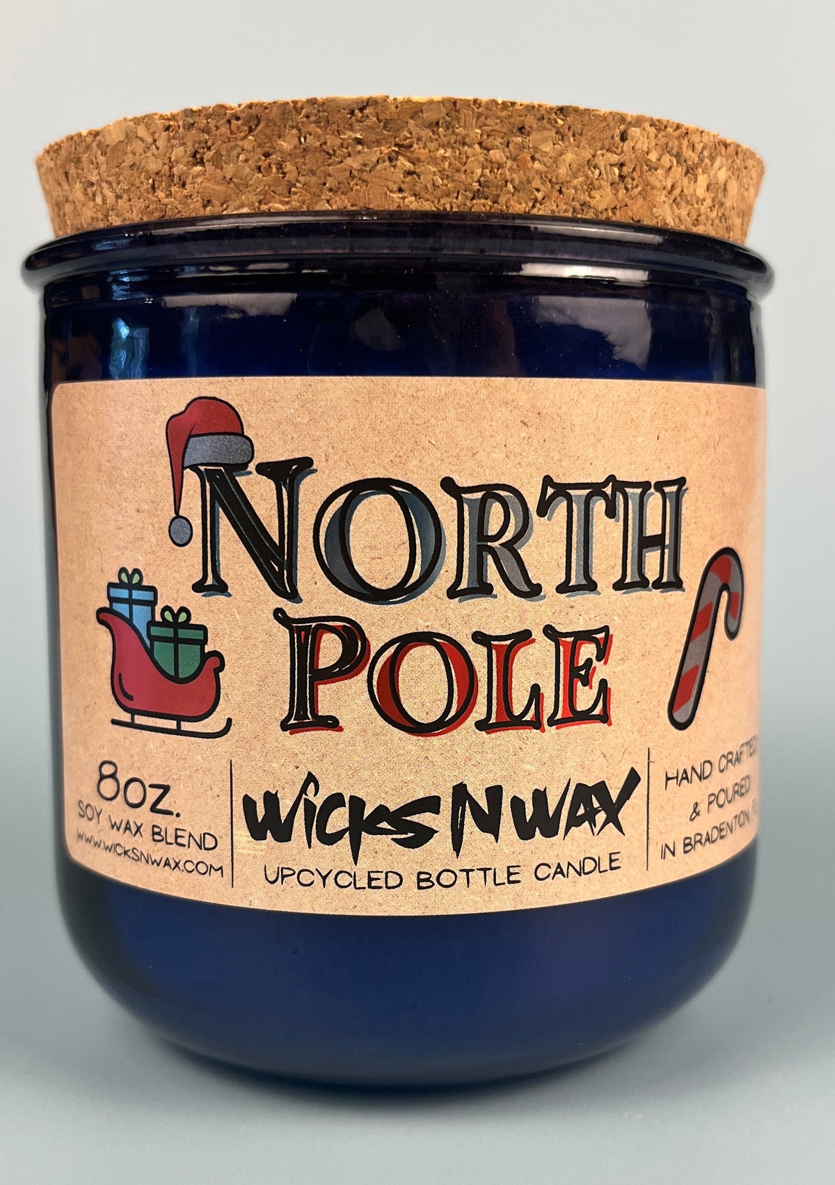 Blue glass candle jar with cork base, North Pole graphic label and 8 oz text.