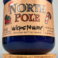 Blue glass candle jar on cork base with North Pole label and WicksNWax text.
