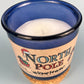 Blue glass candle jar top view with visible wax pool, wick, and North Pole label.