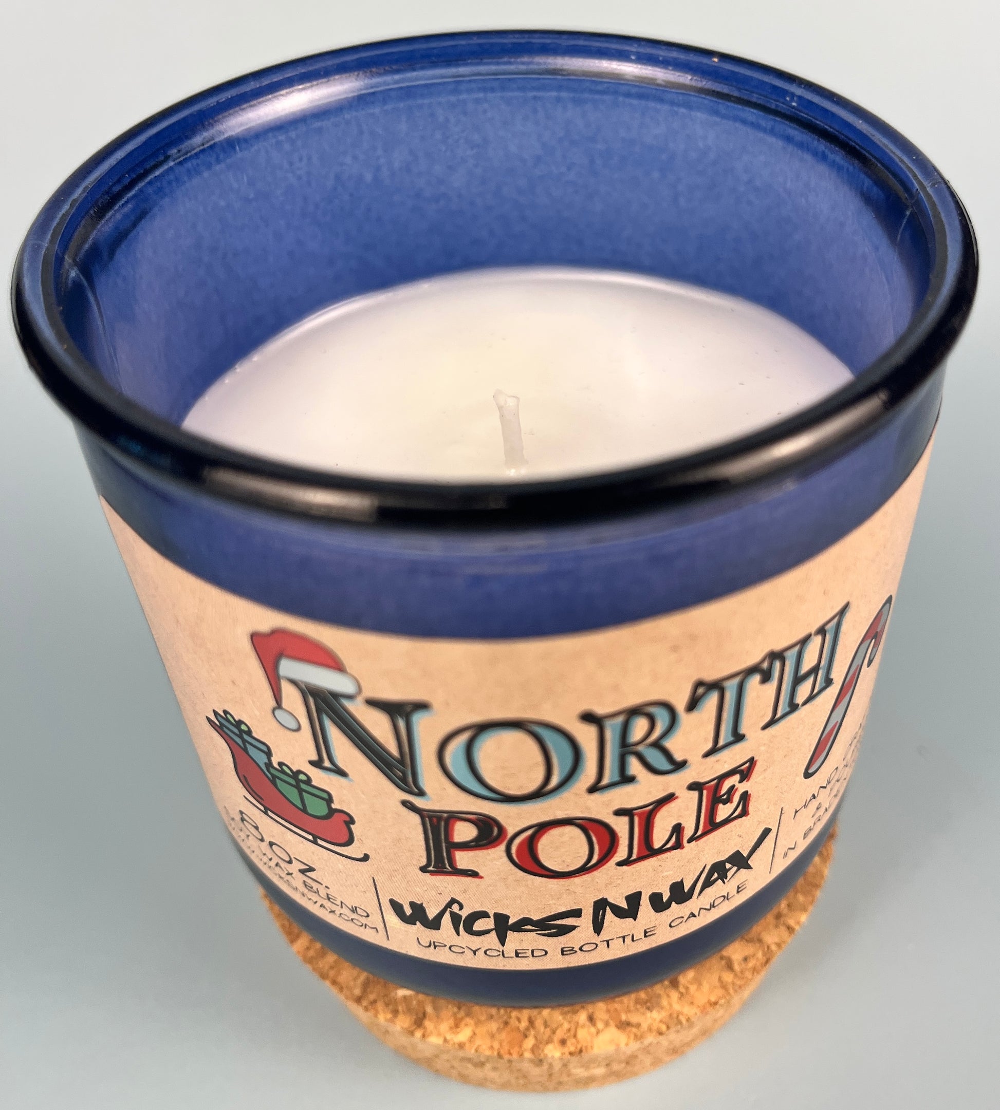 Blue glass candle jar top view with visible wax pool, wick, and North Pole label.