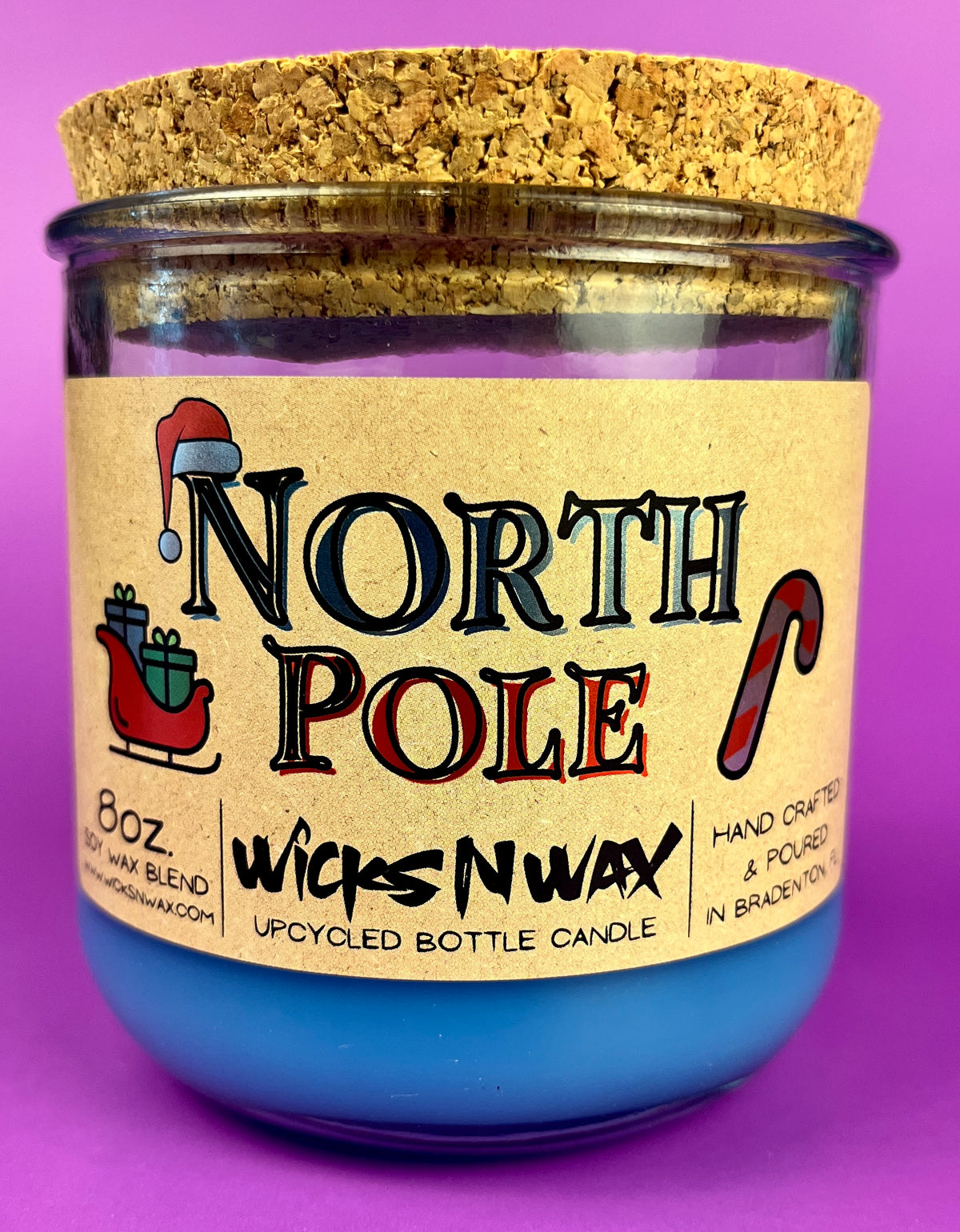 Recycled bottle candle with blue wax and kraft label; cork base visible