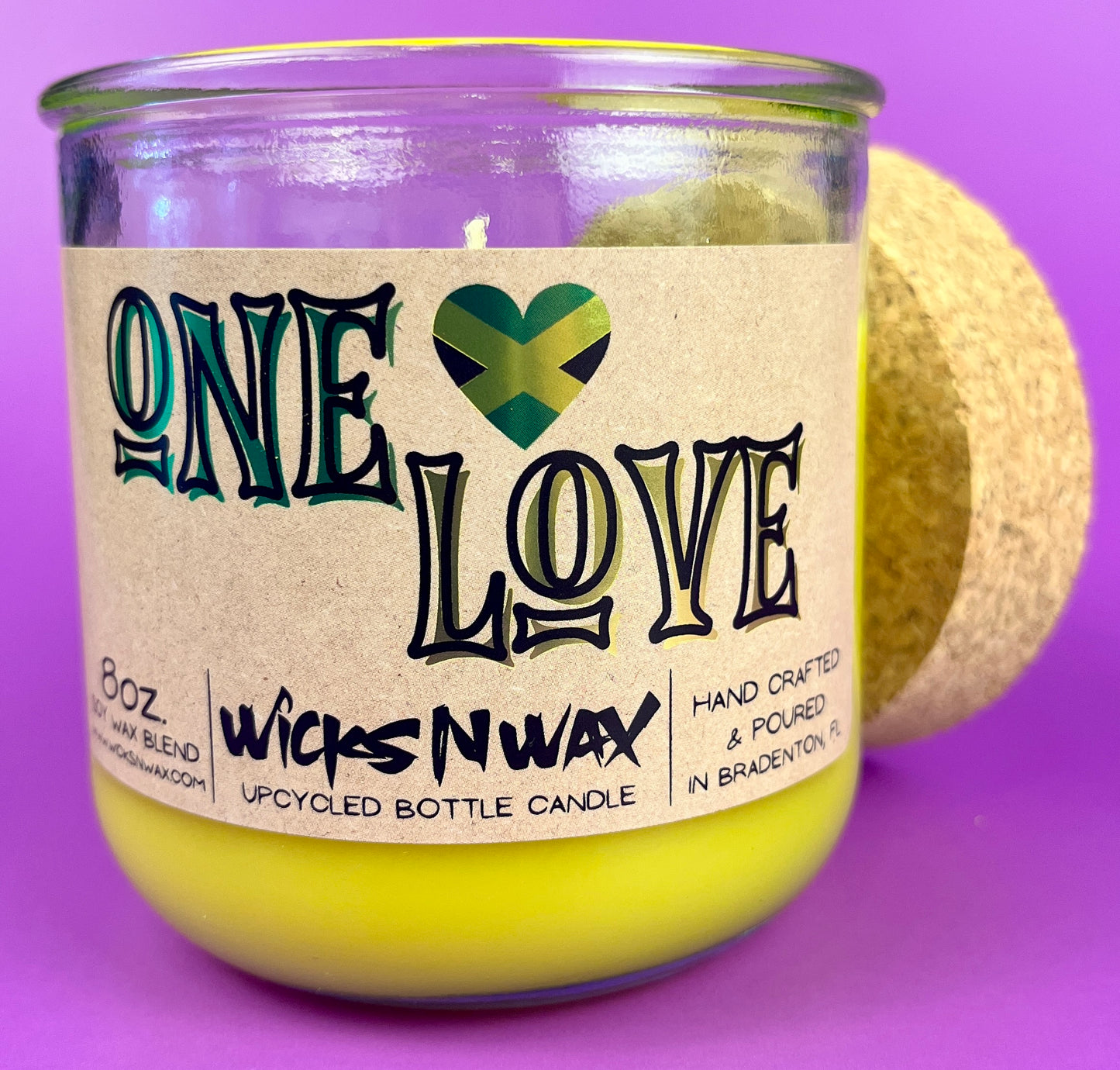 Recycled glass candle jar with yellow wax and One Love label.