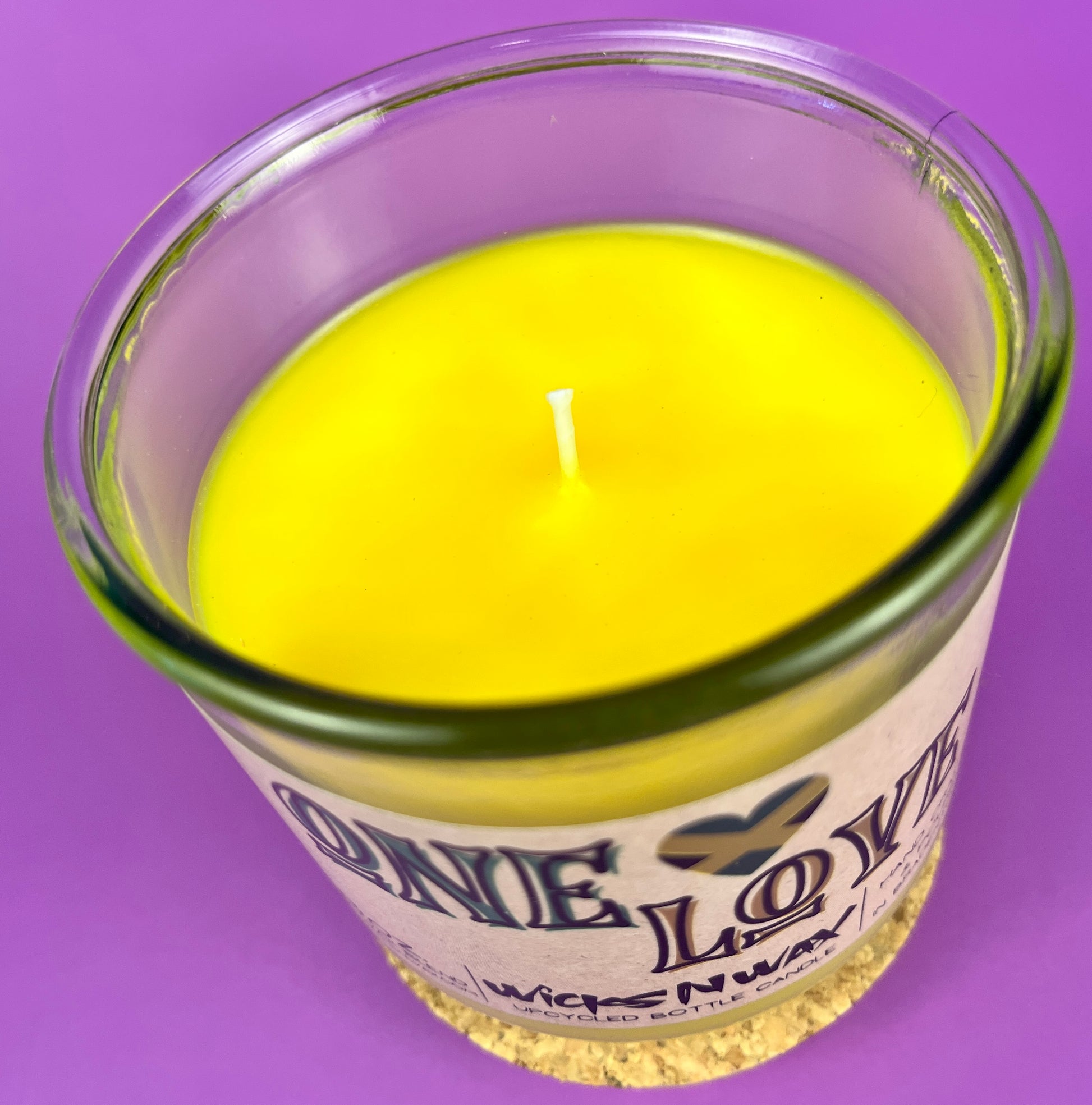 Recycled glass candle top view with yellow wax and centered wick.
