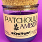 Recycled glass candle in clear jar with purple wax and cork lid, Patchouli Amber label.
