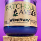 Recycled glass candle in clear jar with purple wax, cork coaster beneath.