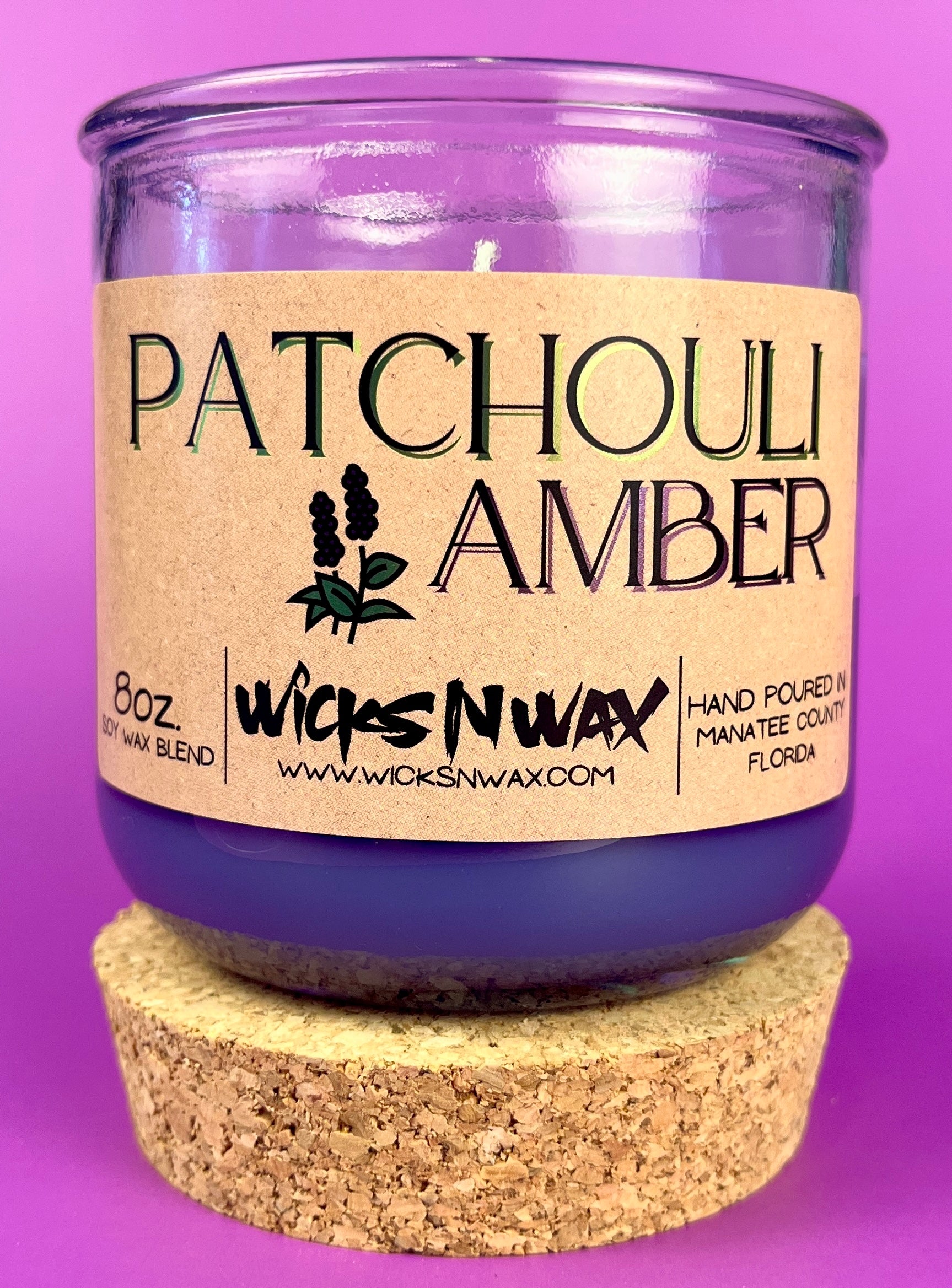 Recycled glass candle in clear jar with purple wax and cork base, front label visible.