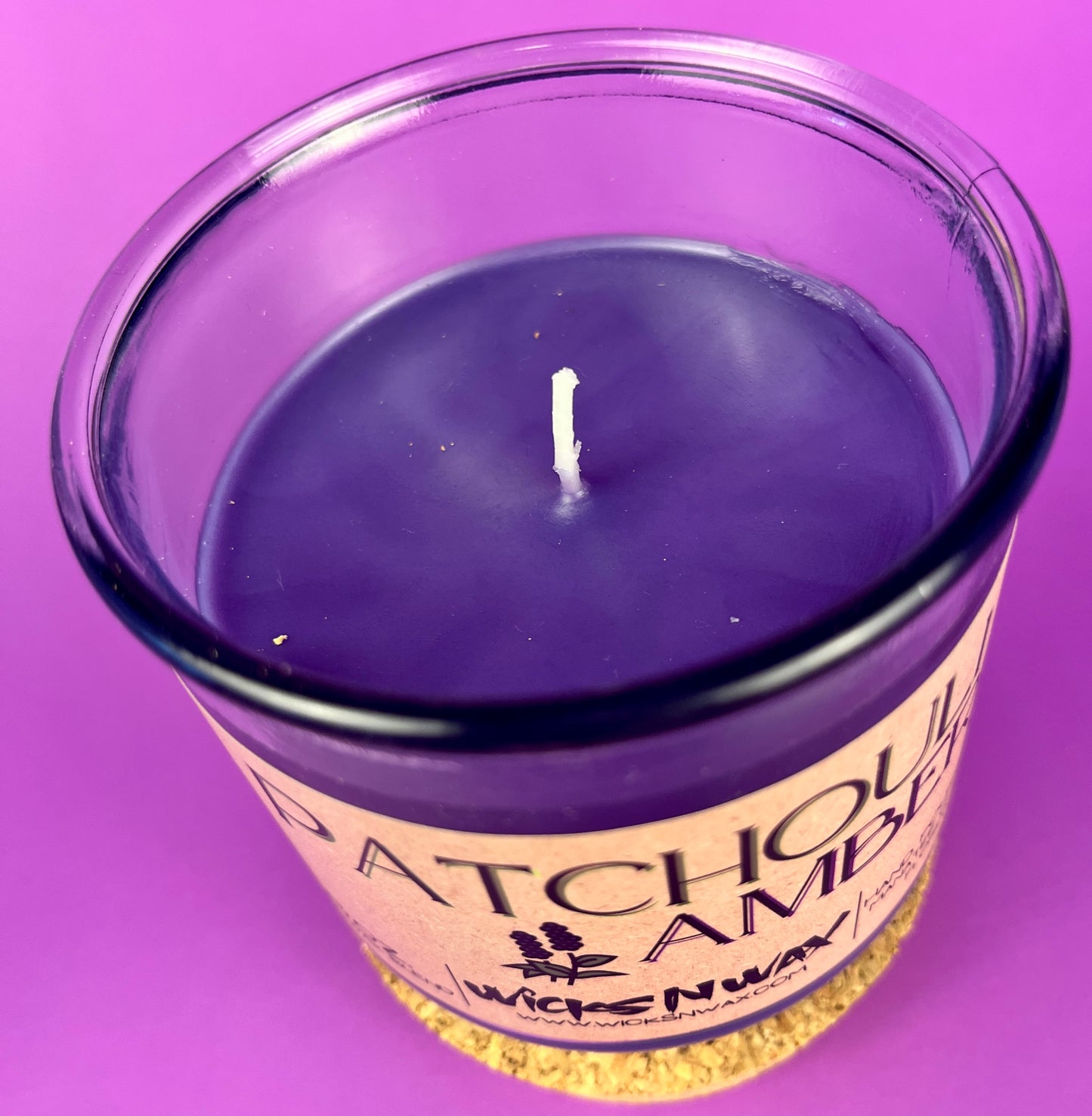 Recycled glass candle with purple wax surface and centered wick in clear jar.