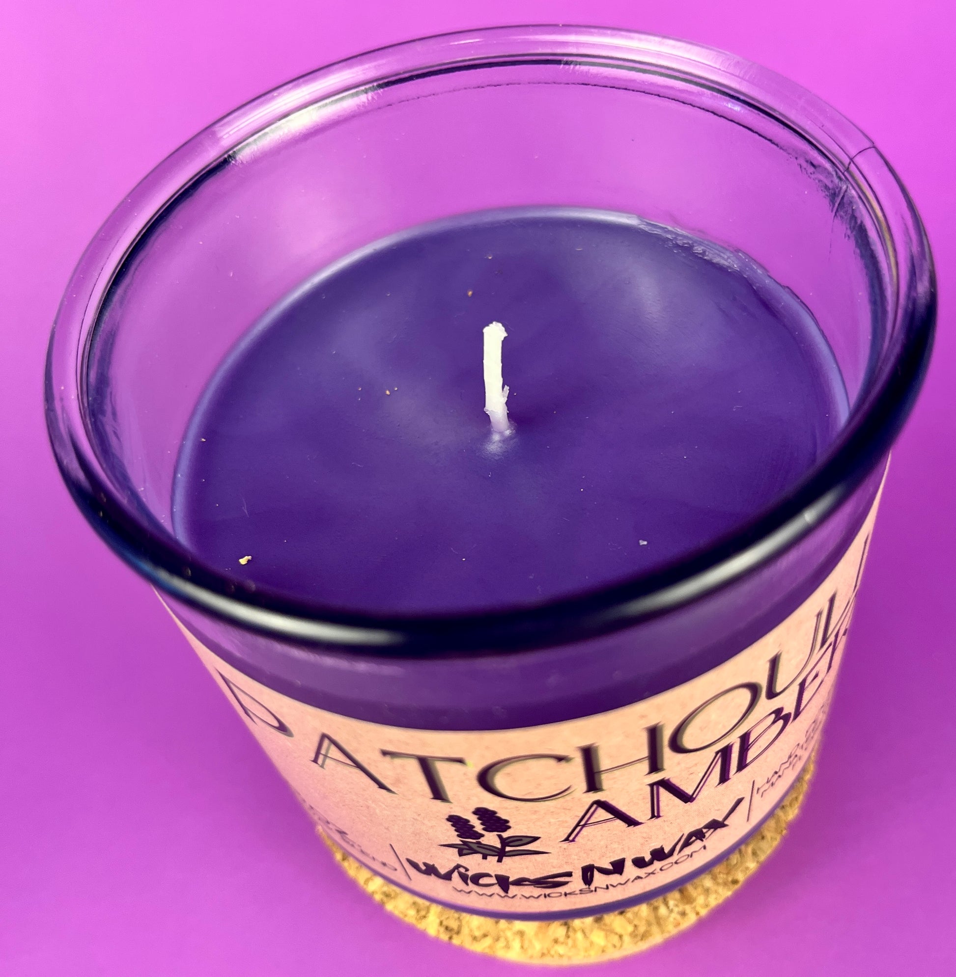 Recycled glass candle with purple wax surface and centered wick in clear jar.