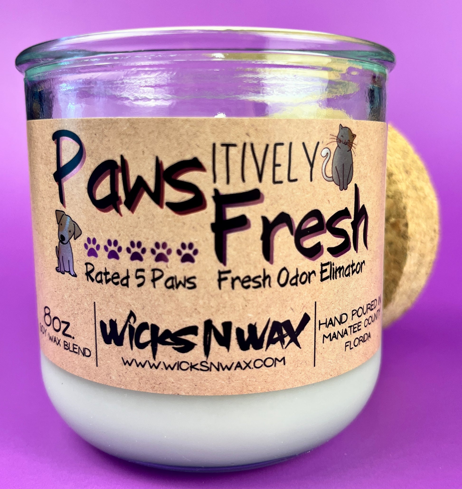 Recycled glass candle with white wax and cork lid, close-up of paw-themed label