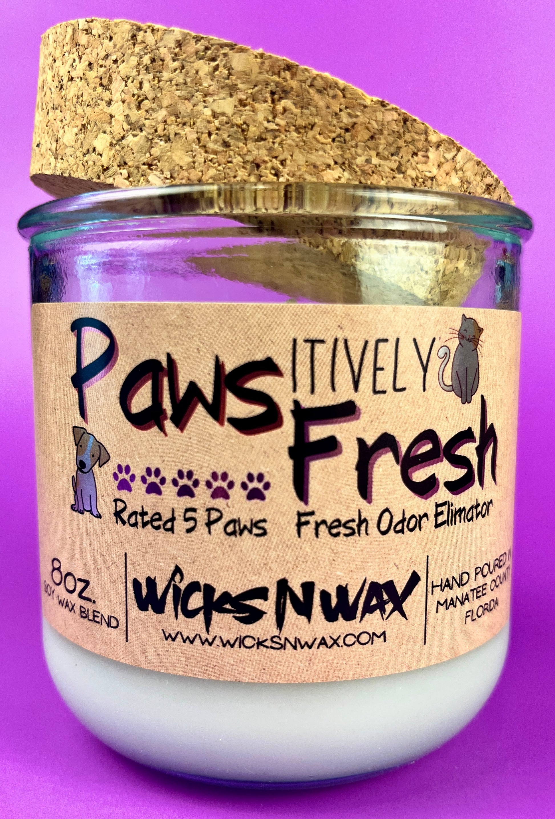 Recycled glass candle with white wax and cork lid, close view of paw-themed label